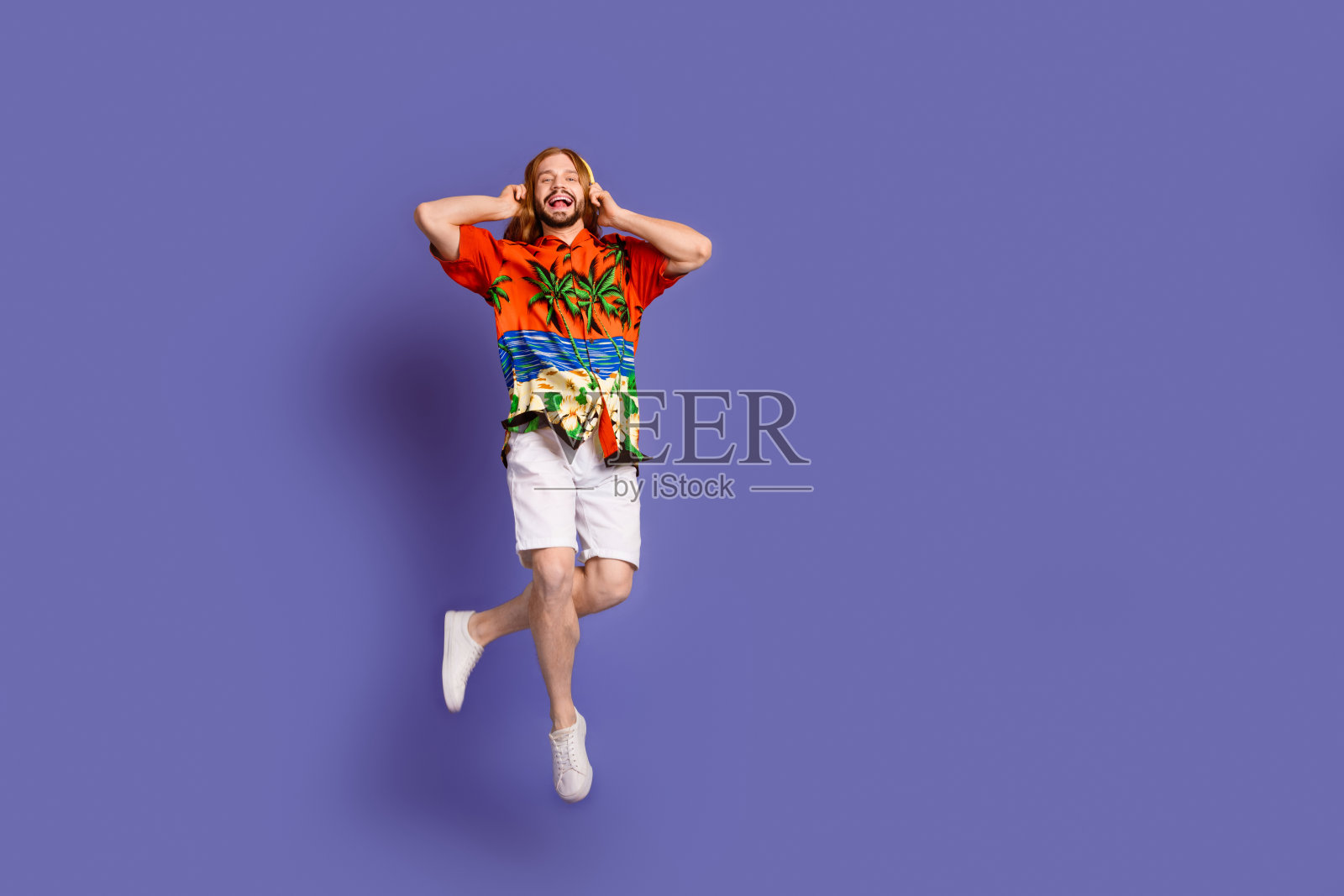 全长照片的飞行男子与红头发穿着印花衬衫触摸耳机享受声音孤立的紫罗兰色背景照片摄影图片