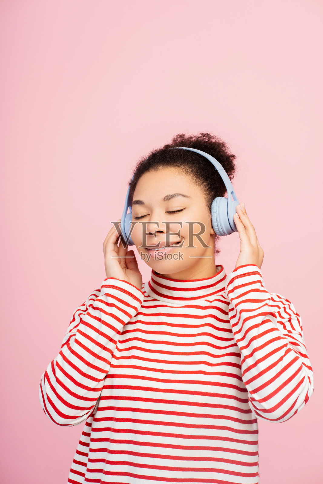 美丽的非裔美国女人，戴着耳机，闭着眼睛听音乐照片摄影图片