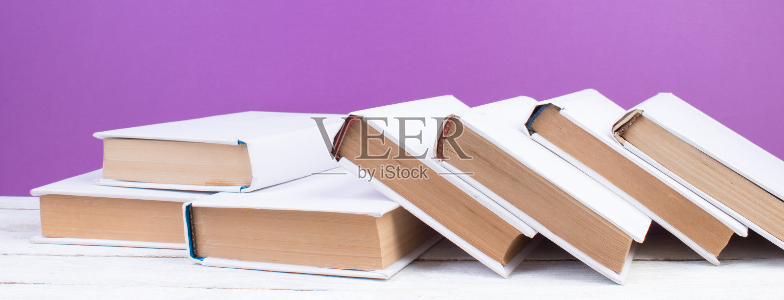 书，木桌上的精装彩色书。紫色的背景。回到学校。文本的复制空间。教育经营理念。照片摄影图片