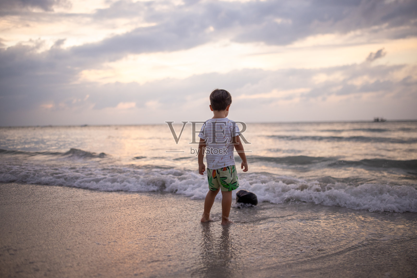 小男孩站在沙滩上照片摄影图片