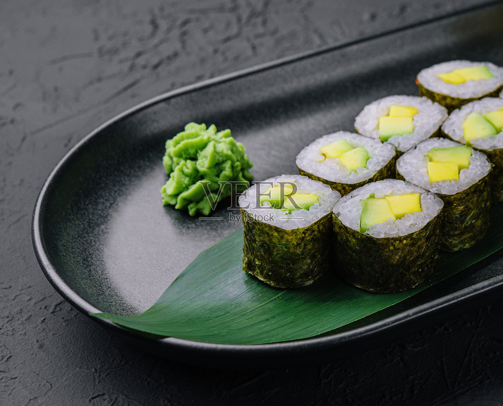 黑盘子上的牛油果寿司卷照片摄影图片