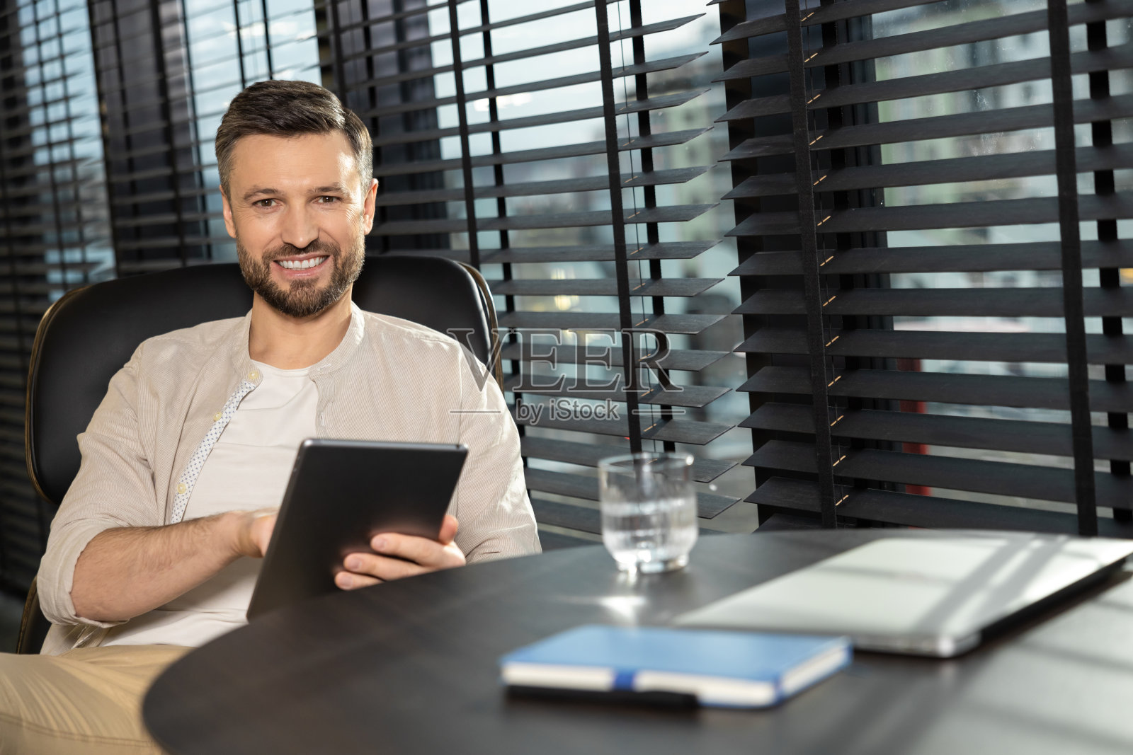 穿着米色衣服、留着胡子的年轻男子在办公室工作照片摄影图片