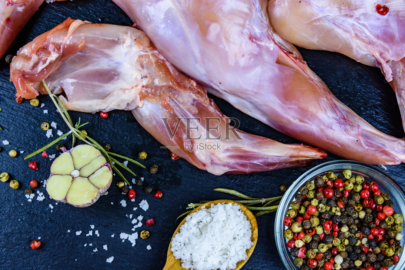 兔肉加胡椒，迷迭香，盐和大蒜，放在石板上。俯视图照片摄影图片