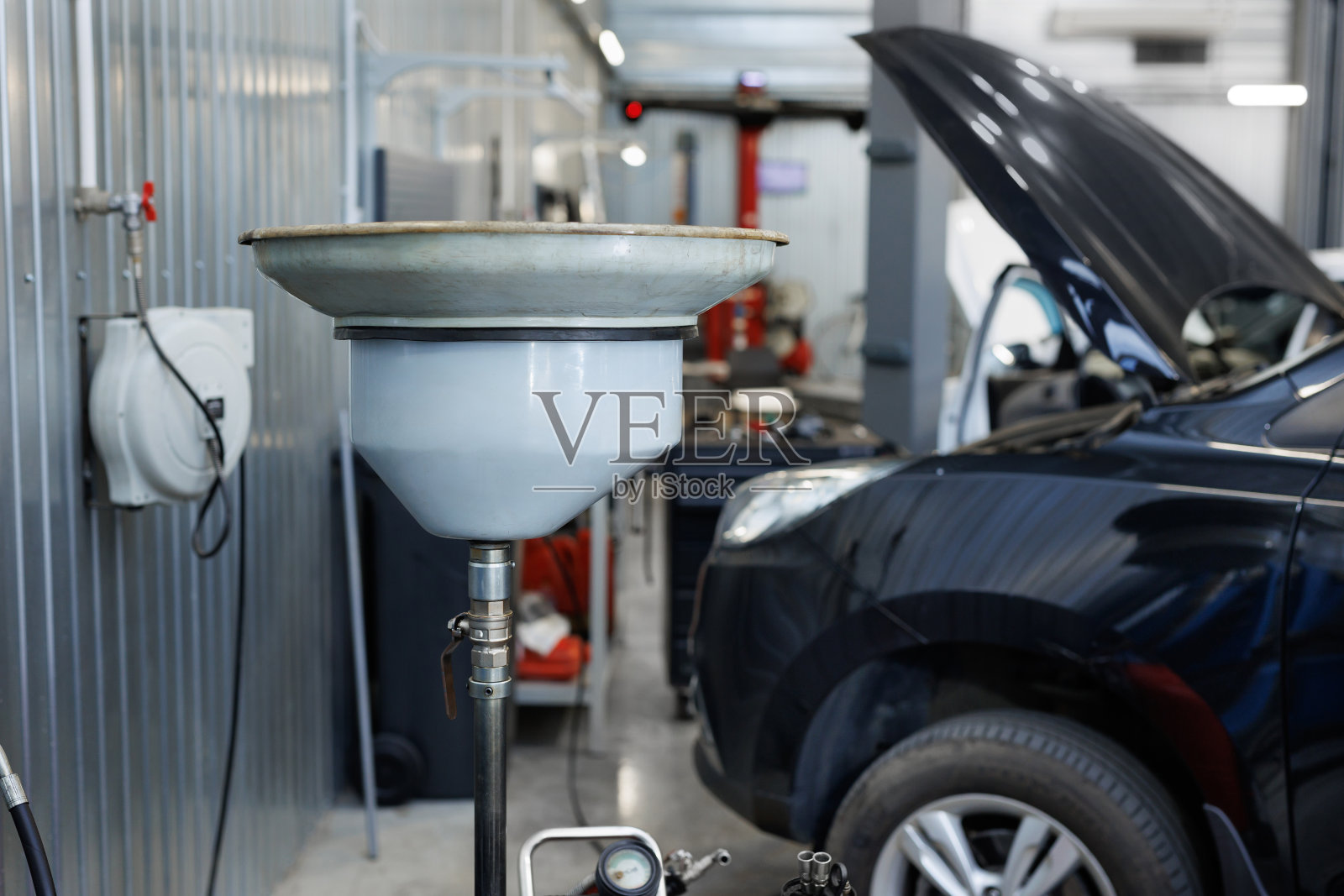 在加油站更换机油。一个在车库车间里放旧机油的碗。照片摄影图片