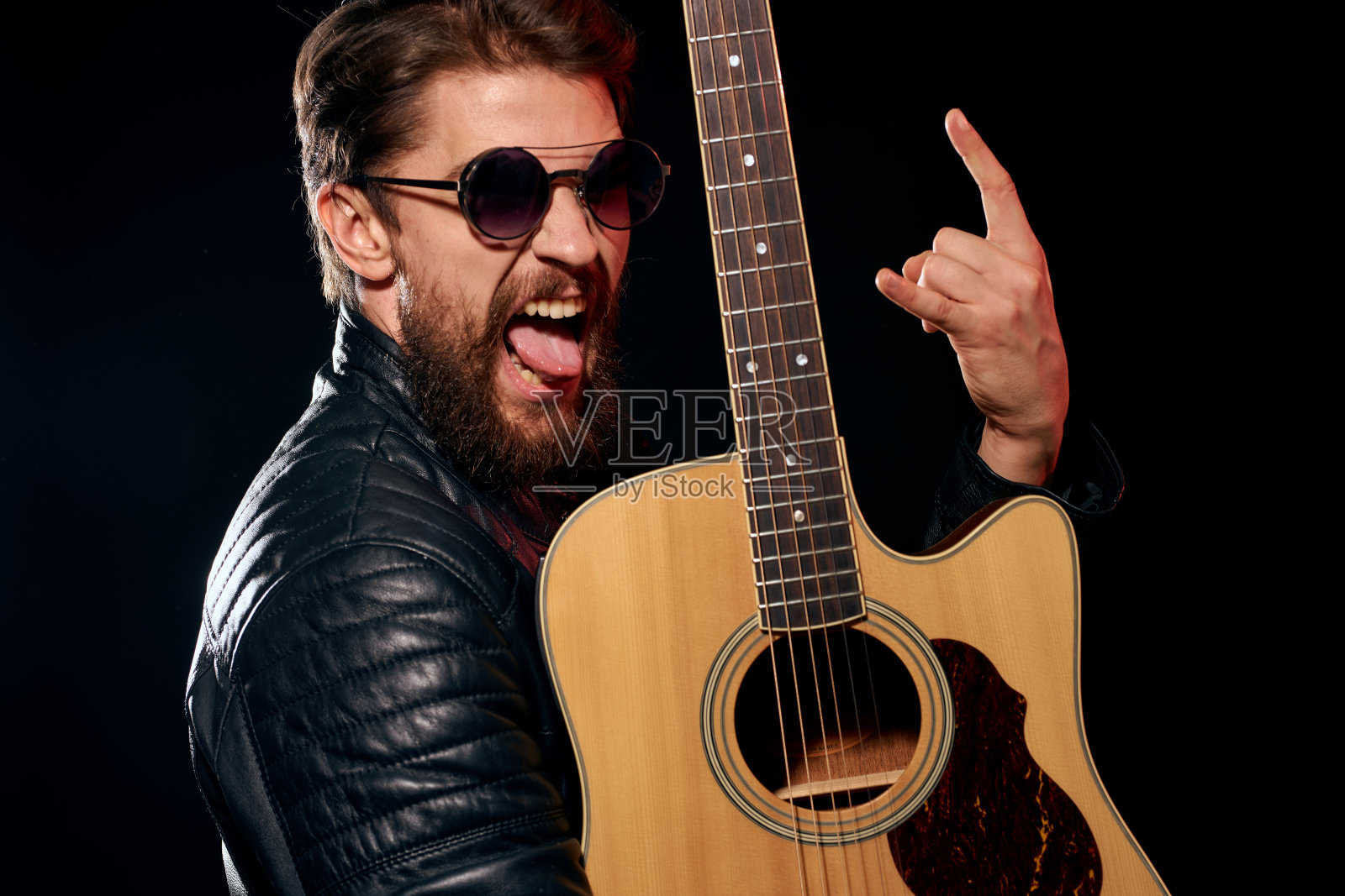 一个手里拿着吉他的男人皮夹克音乐表演摇滚明星现代风格的黑色背景照片摄影图片