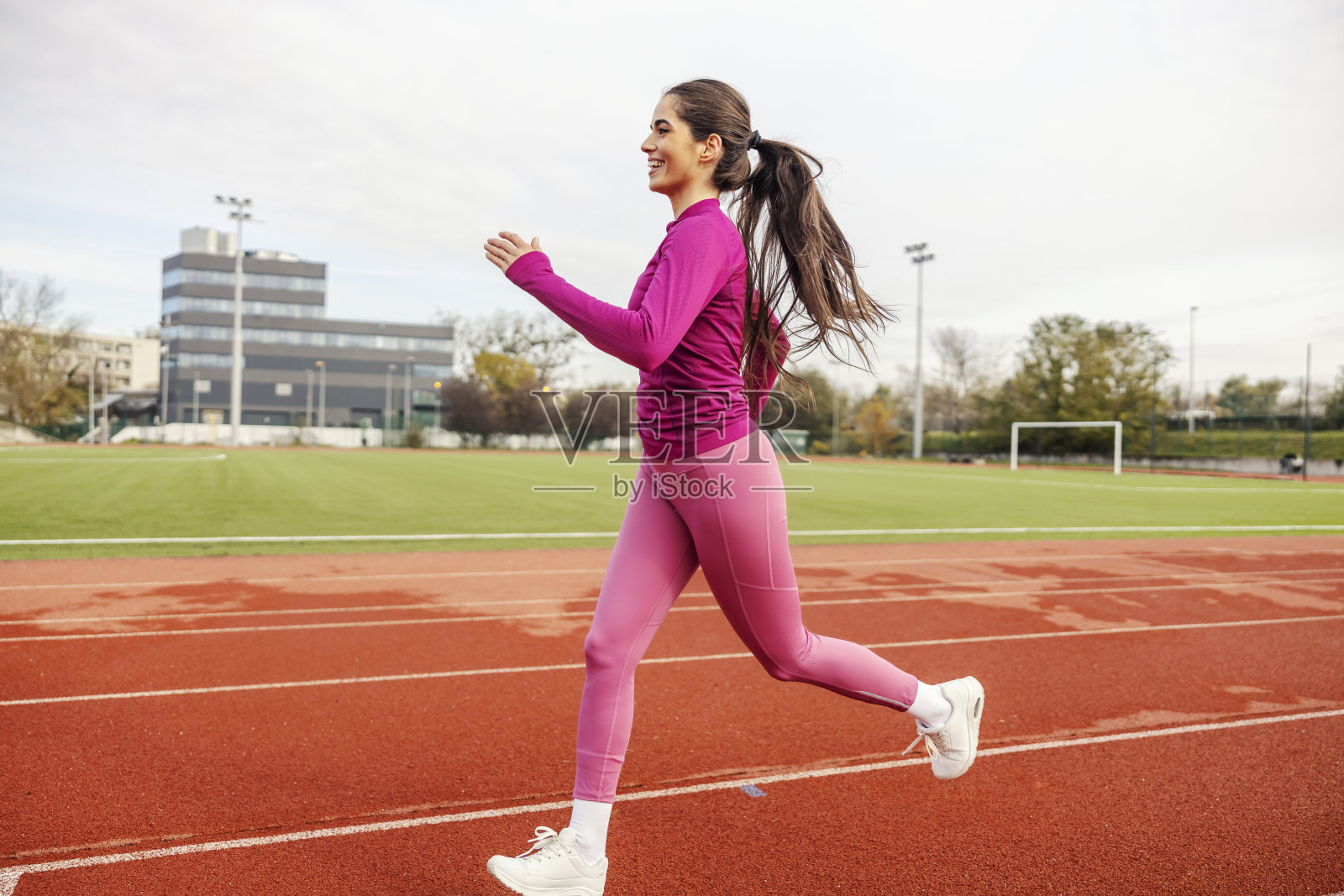 一位健康的女运动员在体育场的跑道上跑步。照片摄影图片