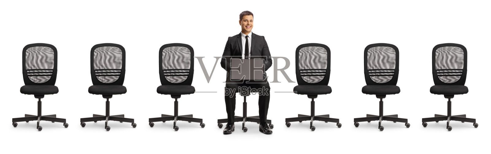 一个商人拿着一台笔记本电脑坐在办公室的椅子上，椅子中间是空的照片摄影图片