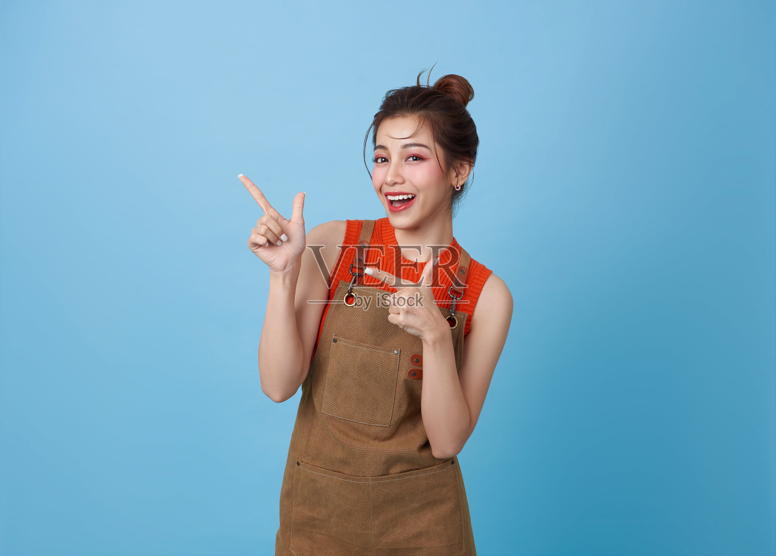 肖像年轻的亚洲咖啡师女人穿着围裙站着，手指在蓝色背景上分开，服务员或企业家快乐，小生意或创业，照片摄影图片