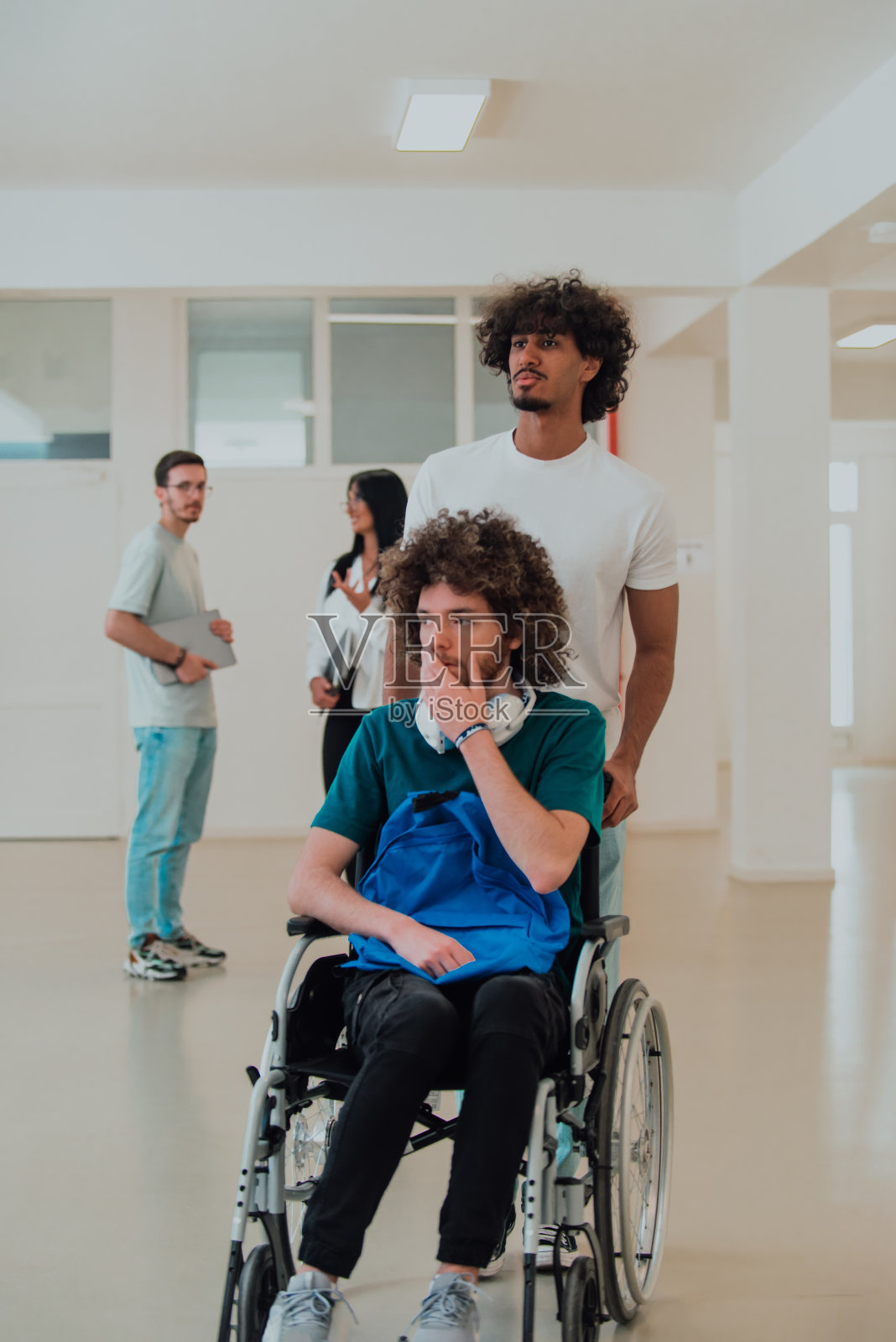 非裔美国学生在学校休息时帮助坐在轮椅上的同事照片摄影图片