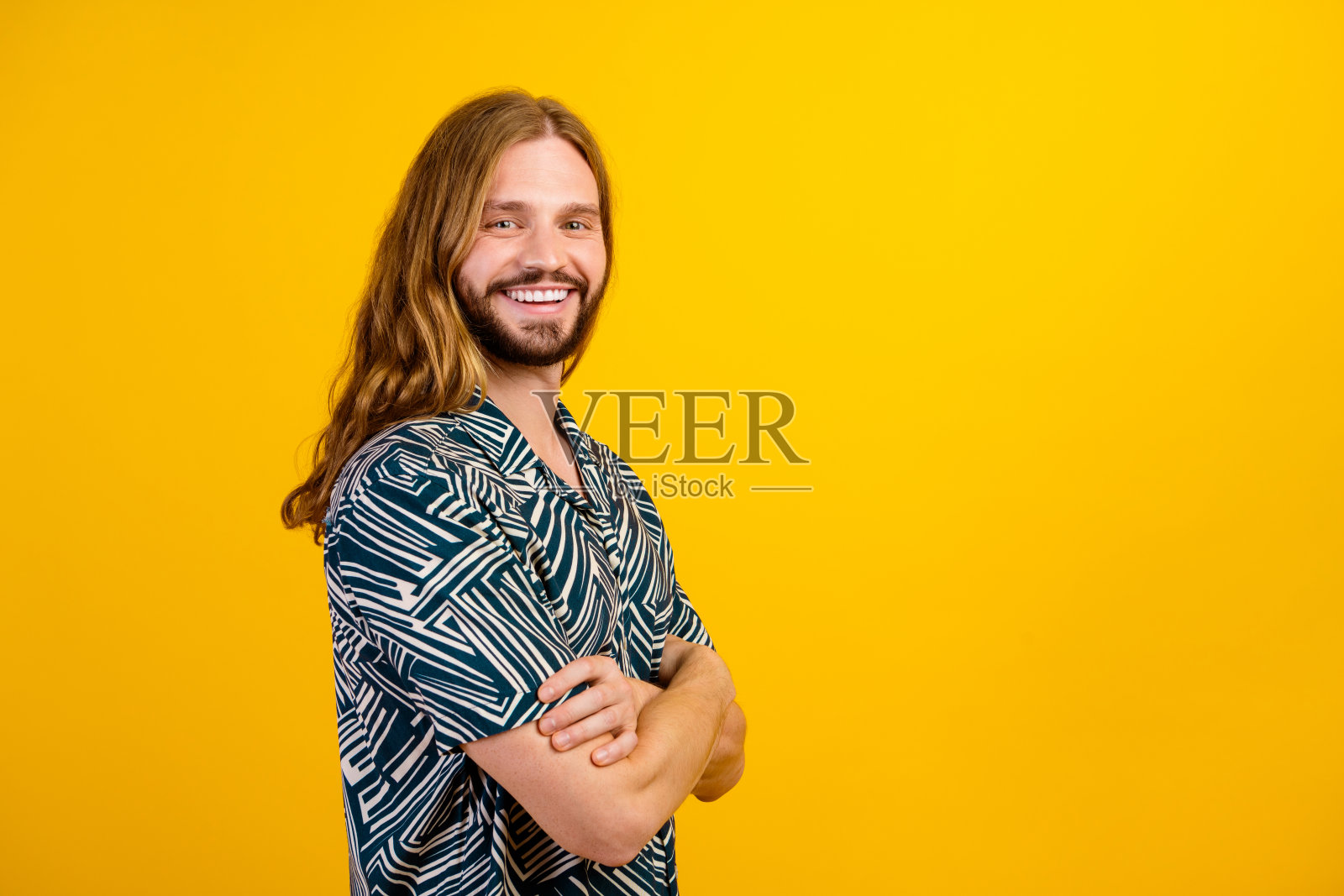 照片中的酷时髦的家伙穿着印花衬衫微笑着双臂交叉空空间孤立的黄色背景照片摄影图片