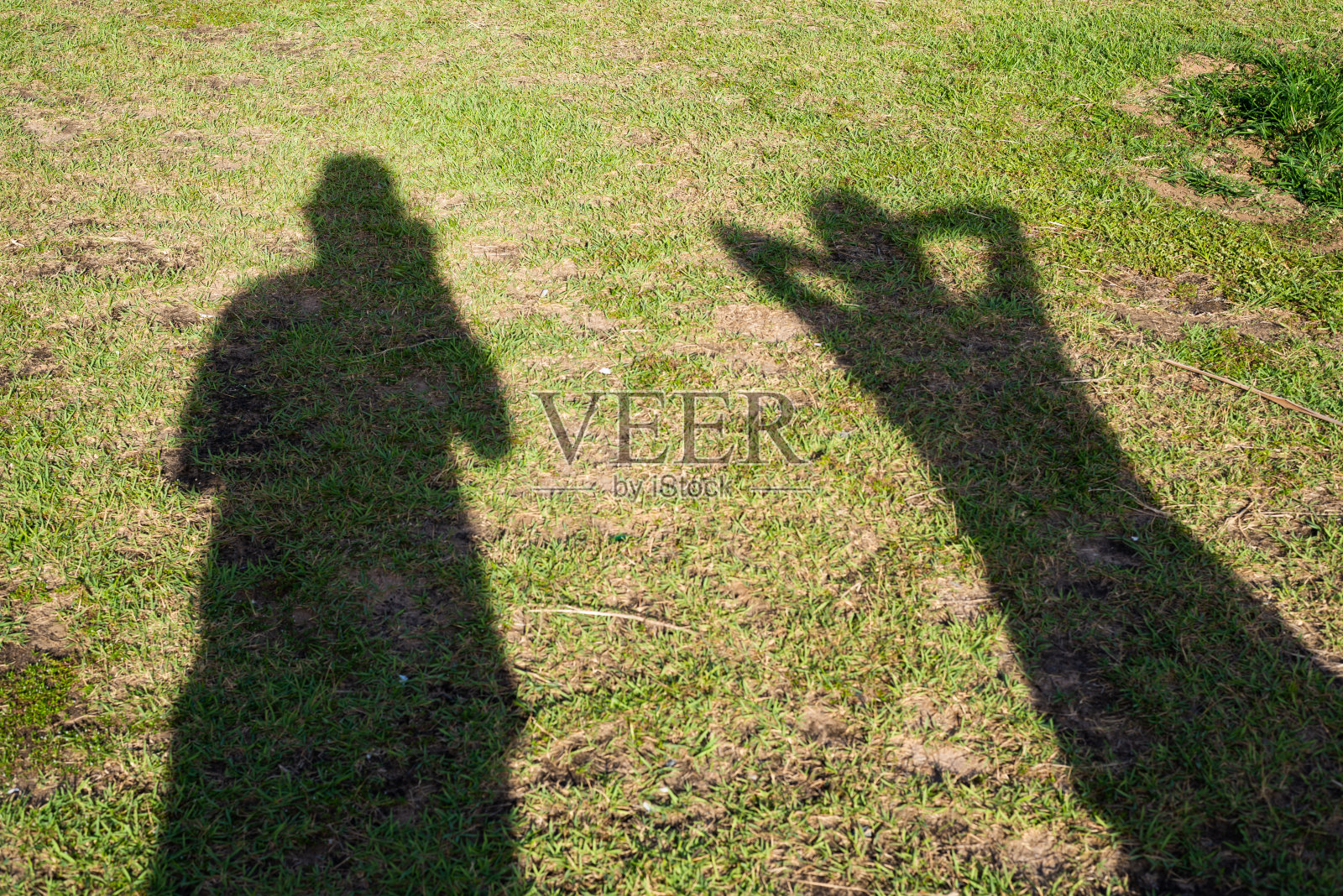 草地上有两个不明身份的人的影子。照片摄影图片