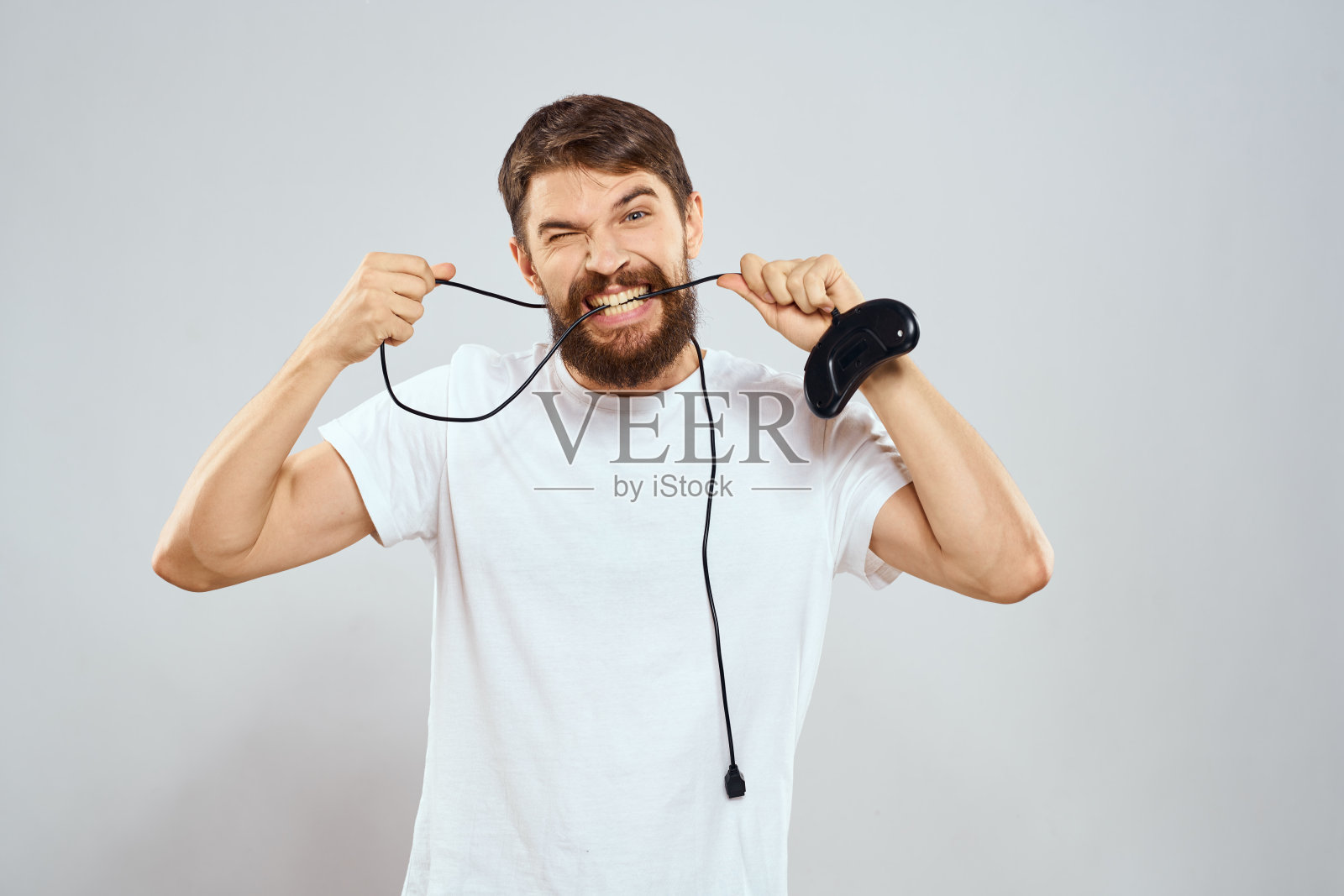 一个手里拿着操纵杆的男人有趣的游戏生活方式白色t恤浅色背景照片摄影图片