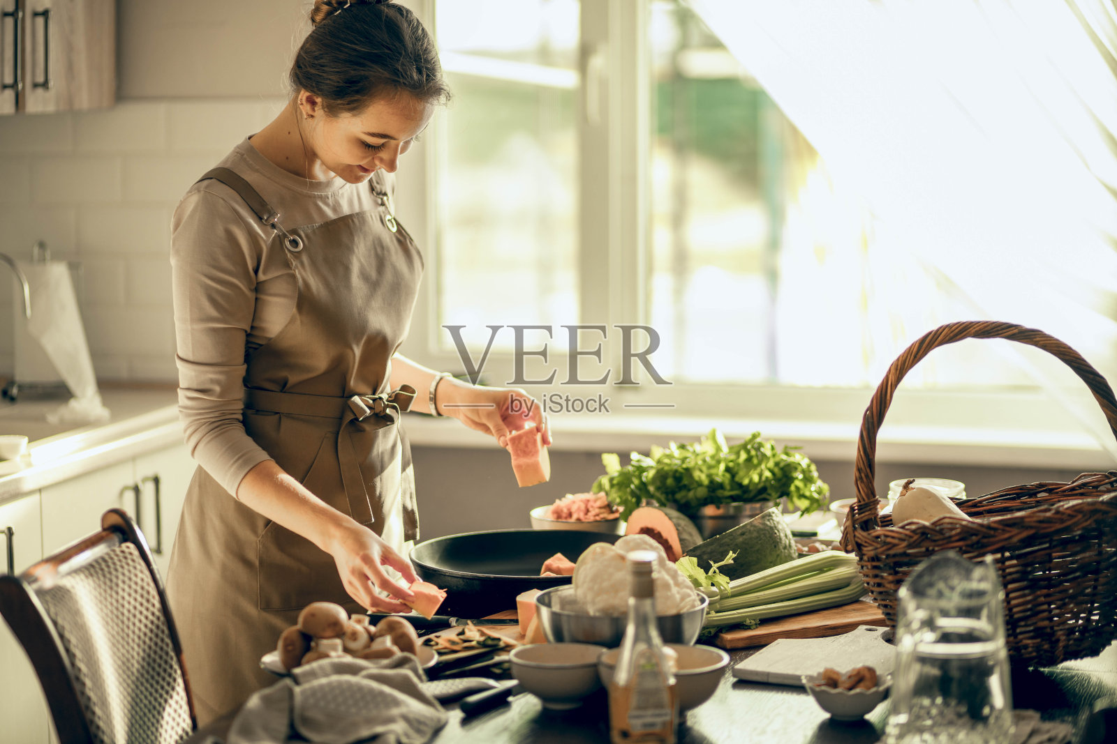 年轻女子把南瓜放在厨房的平底锅里烤。健康营养的概念照片摄影图片