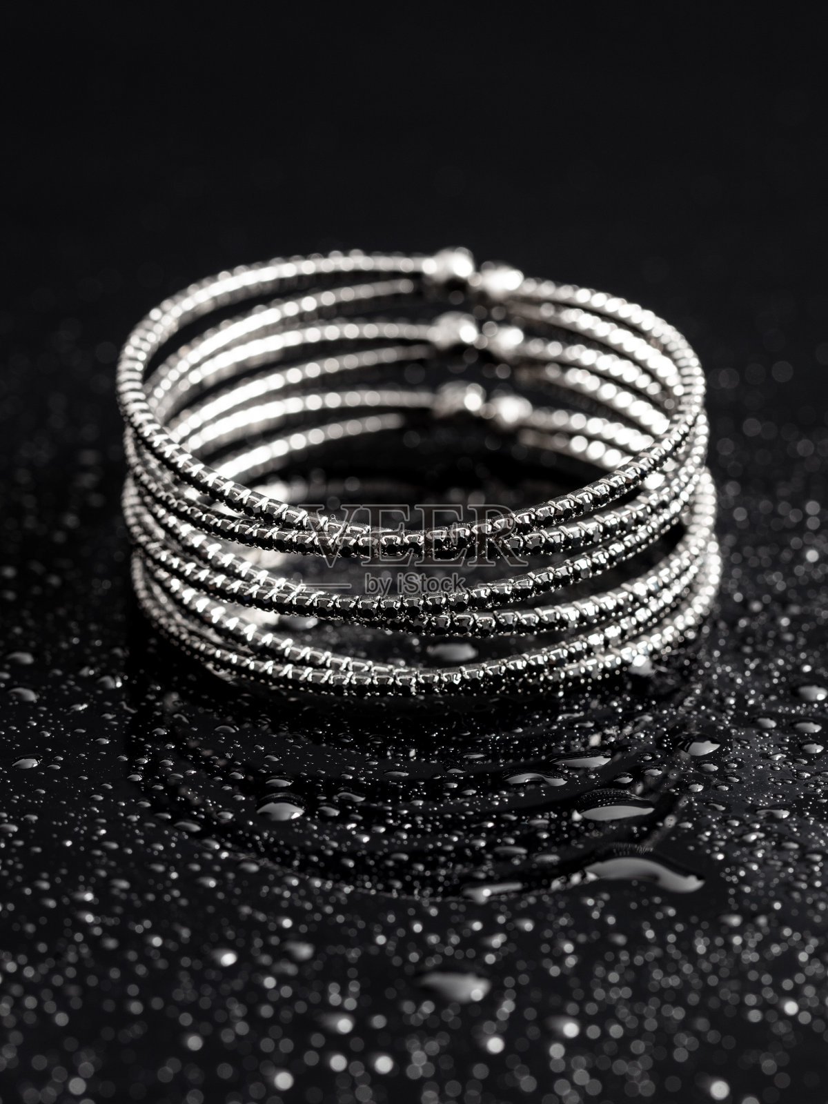 黑色背景上的水滴银色手镯照片摄影图片