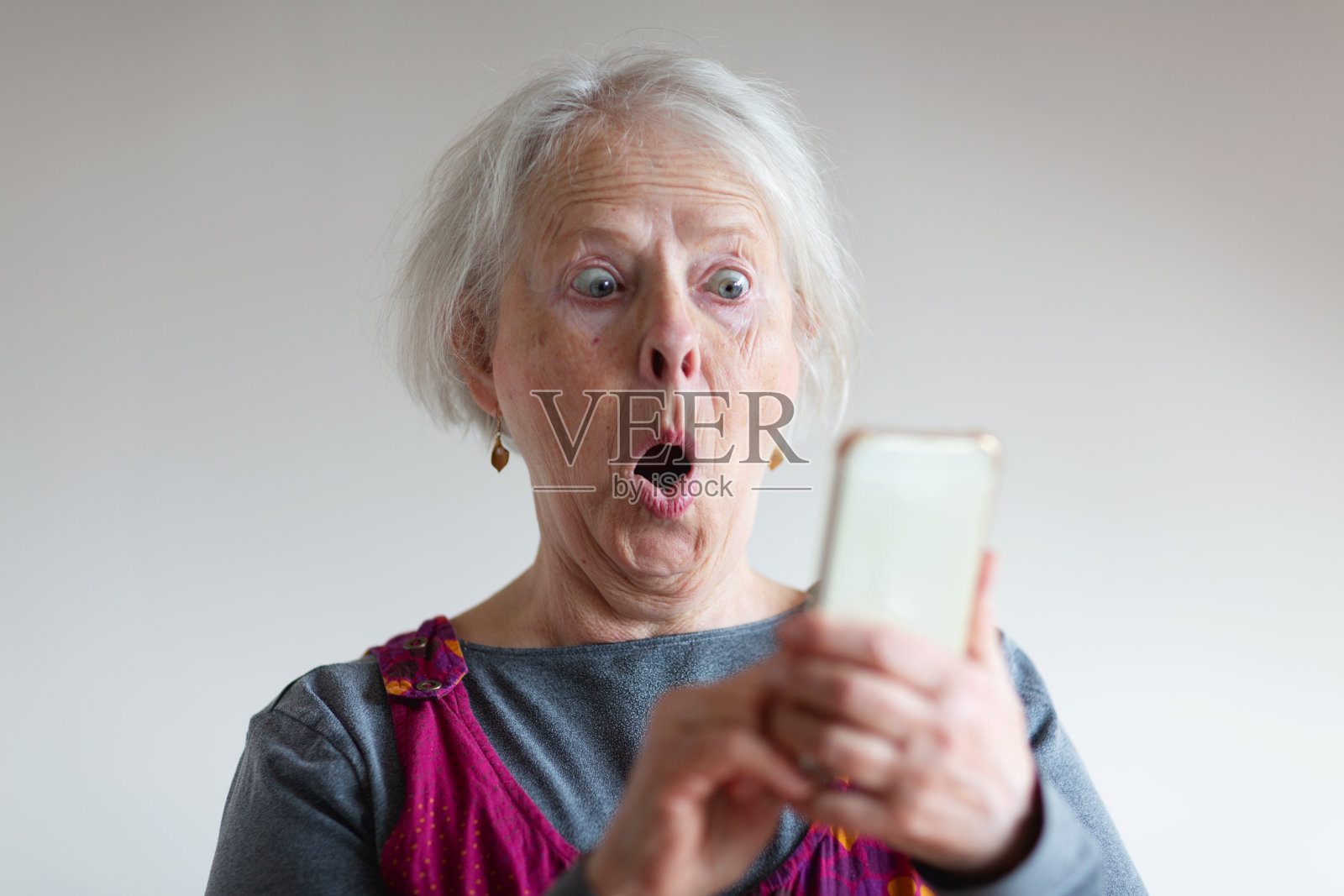 高级女性在使用电话时感到惊讶照片摄影图片