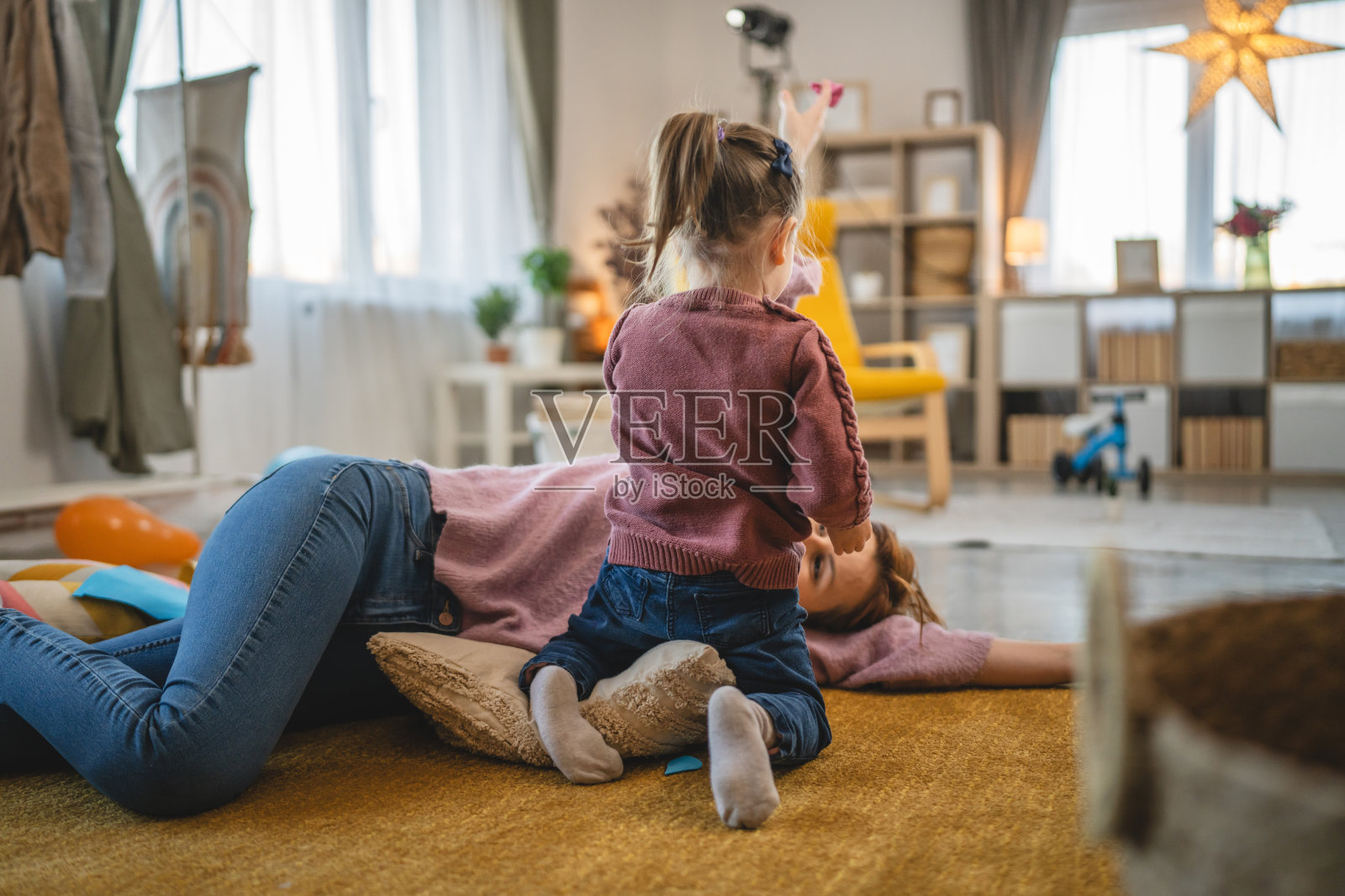 母亲和女儿蹒跚学步的孩子在家里房间的地板上玩耍照片摄影图片