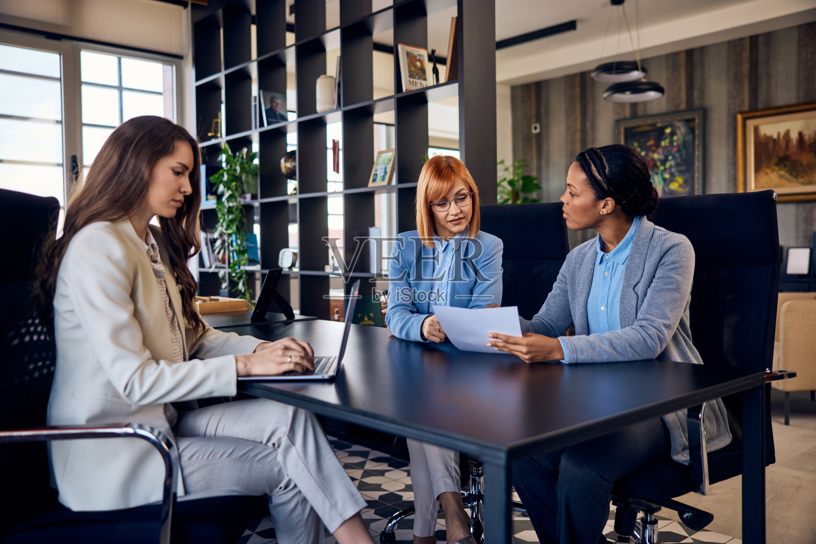 一群三个女人，在办公室工作，开会，穿着优雅。照片摄影图片