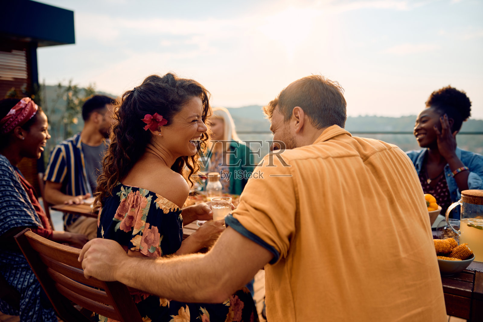 一对幸福的夫妇在露台上与朋友共进午餐时谈笑风生，照片摄影图片