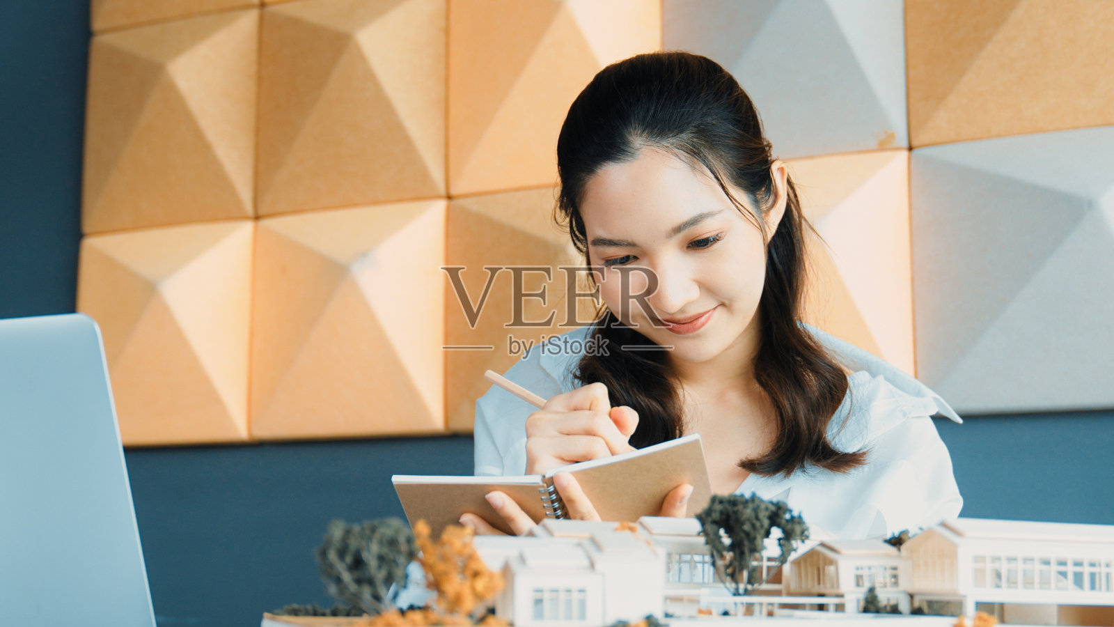 亚洲建筑师在检查建筑模型时做笔记。操纵器。照片摄影图片