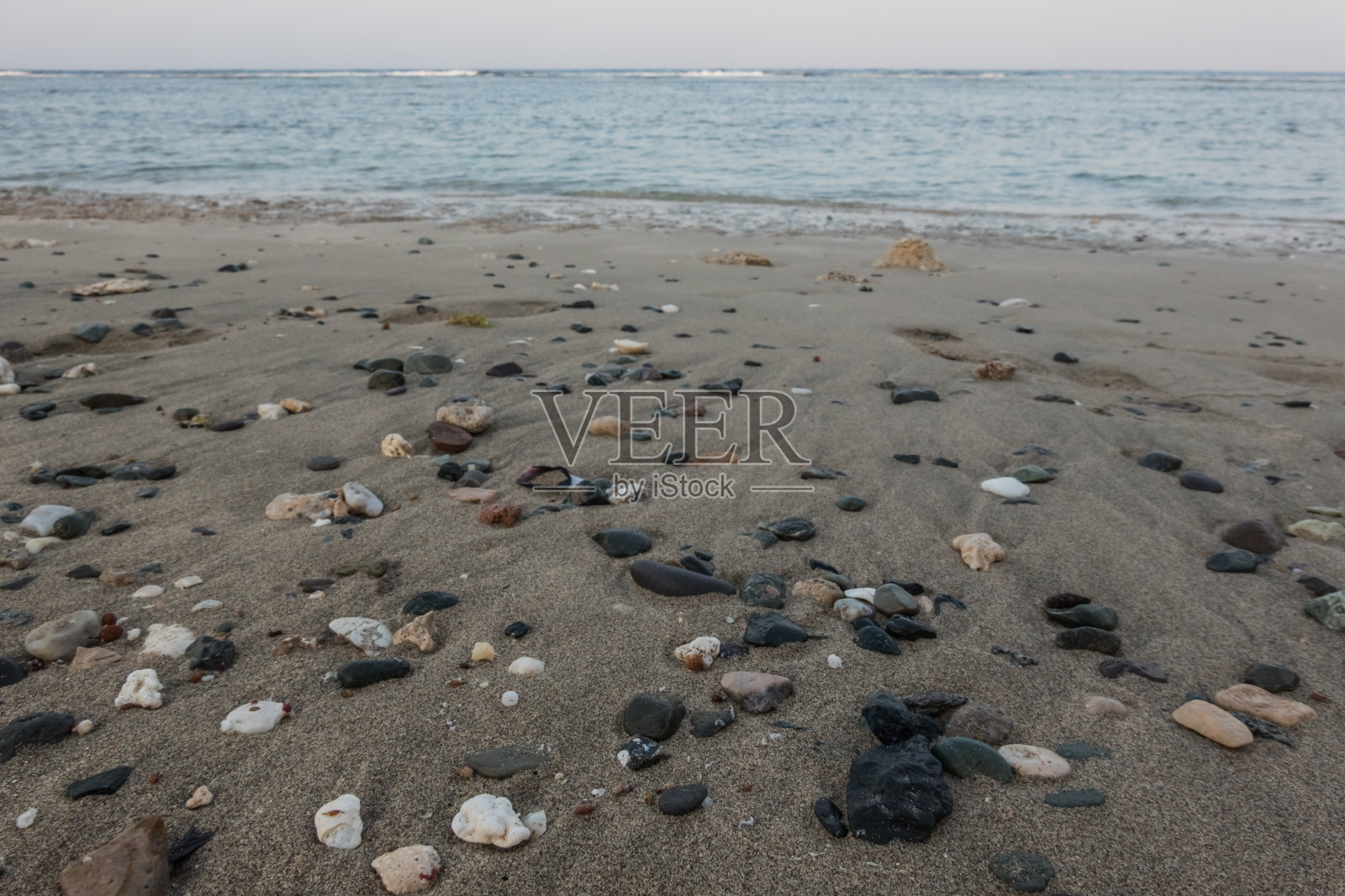 退潮后，海滩上的细沙中有许多五颜六色的石头和珊瑚照片摄影图片