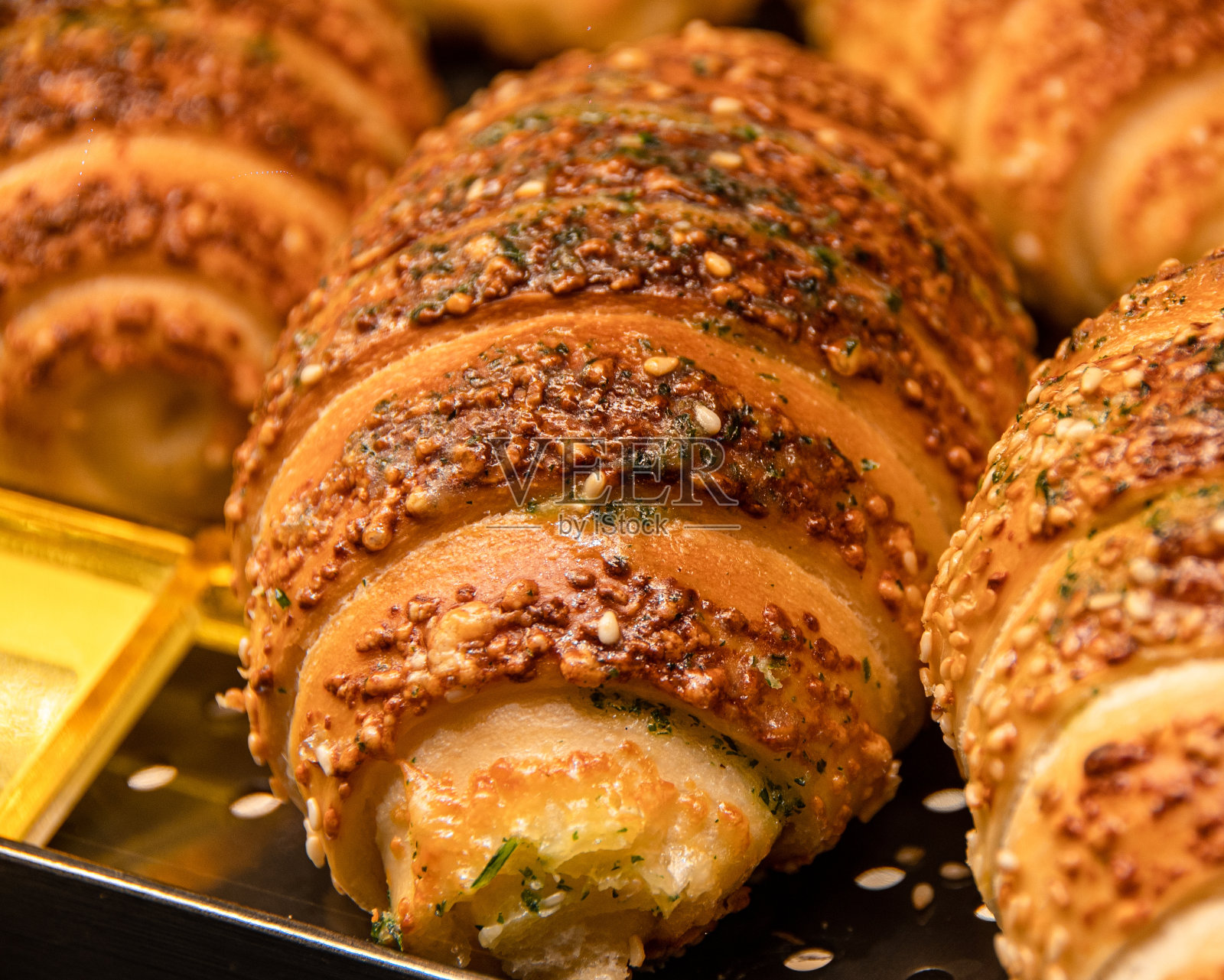 形状精美的美味面包放在钢托盘上，被温暖的灯光照亮照片摄影图片