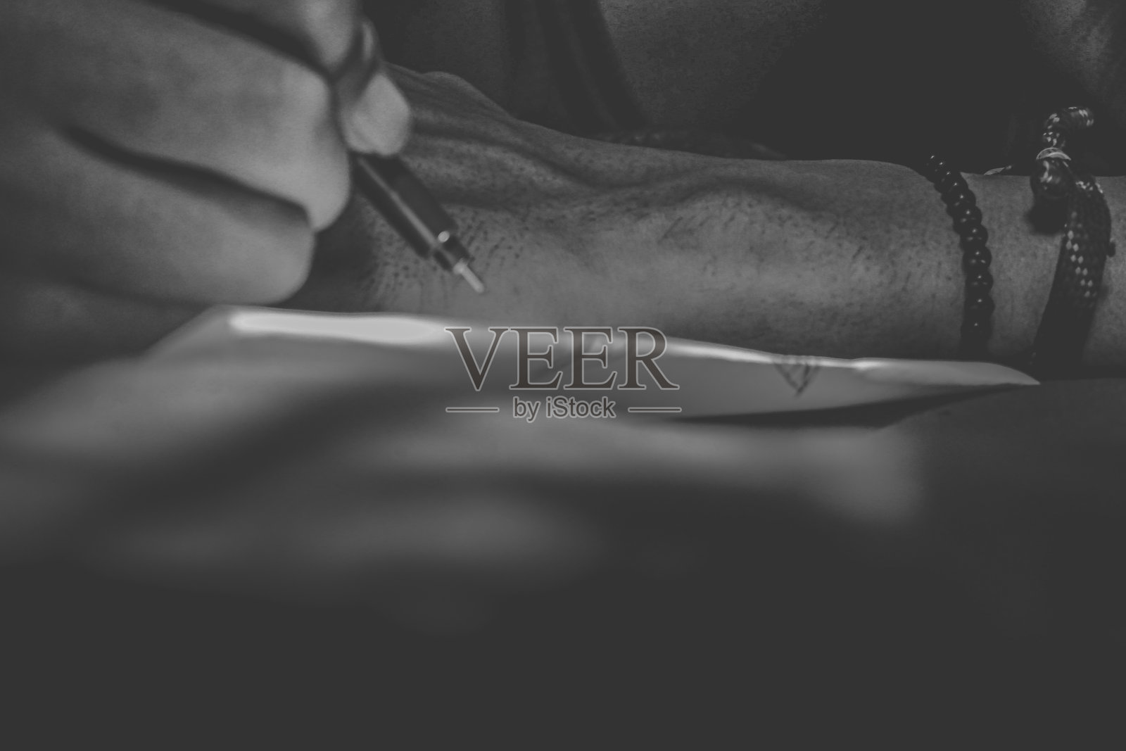 一个男人在桌子上用笔写字的特写镜头照片摄影图片