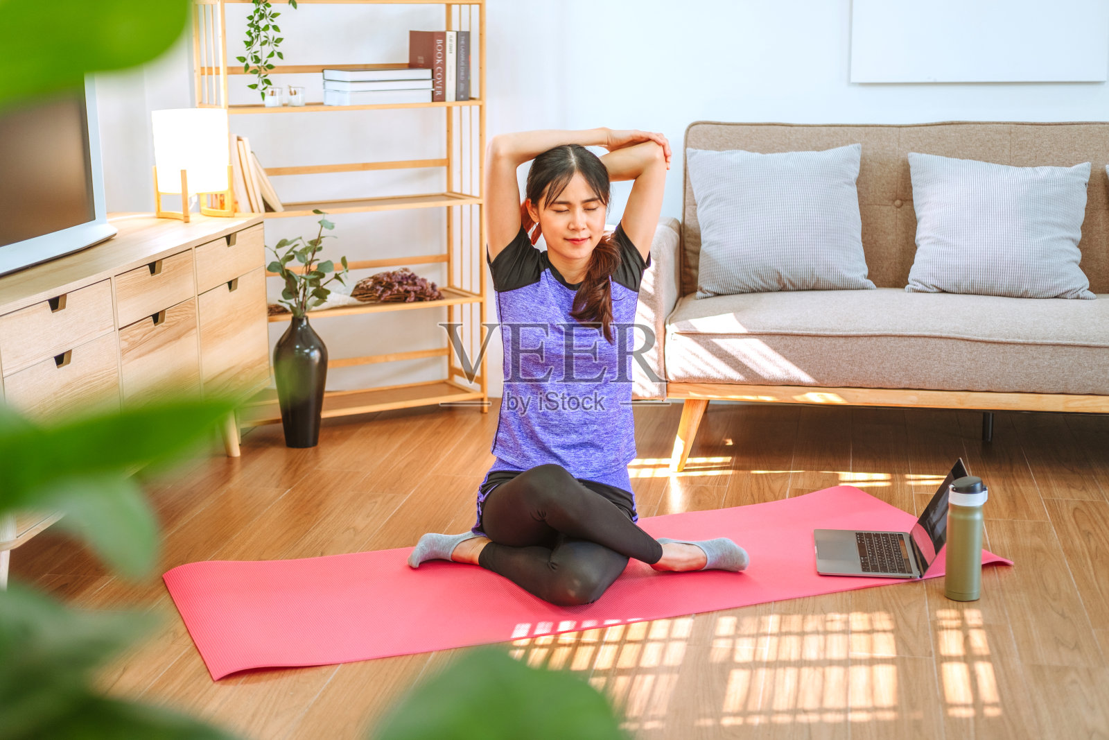 年轻的亚洲健康女性在家里用笔记本电脑锻炼照片摄影图片