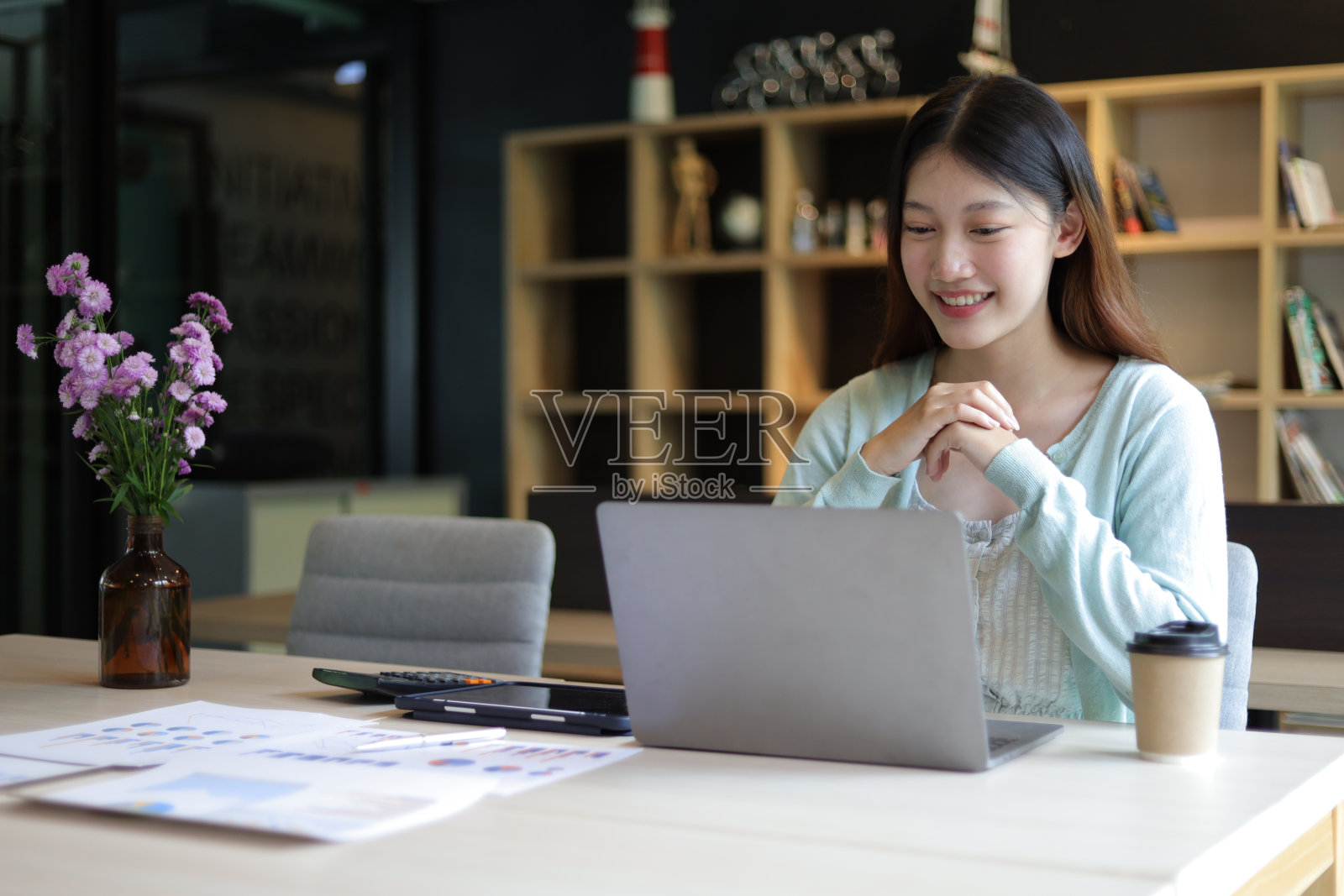 在大学图书馆用笔记本电脑上网学习的学生。亚洲女性在办公室用笔记本电脑工作。照片摄影图片