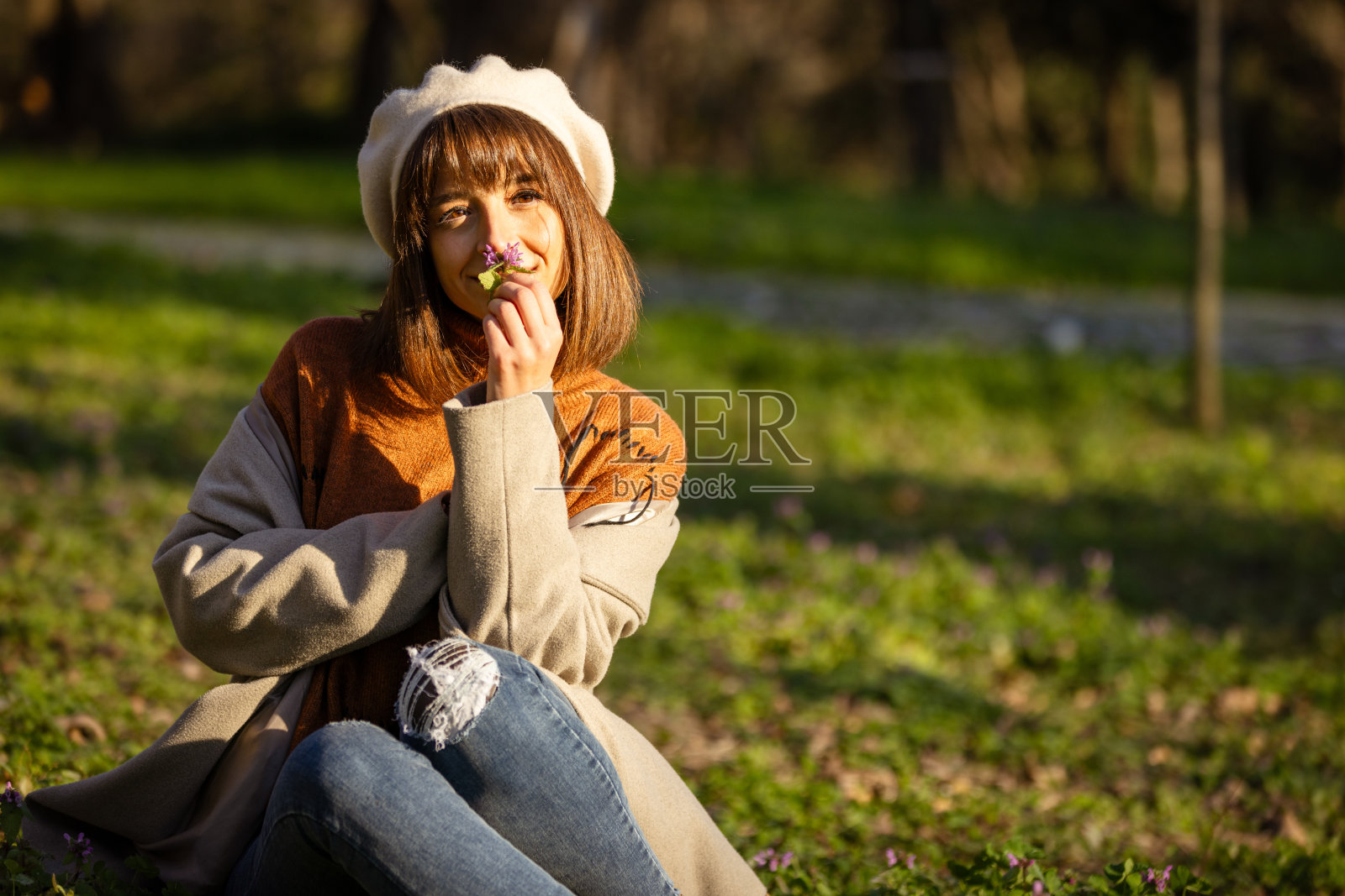 美丽的年轻女士正坐在公园的草地上。照片摄影图片