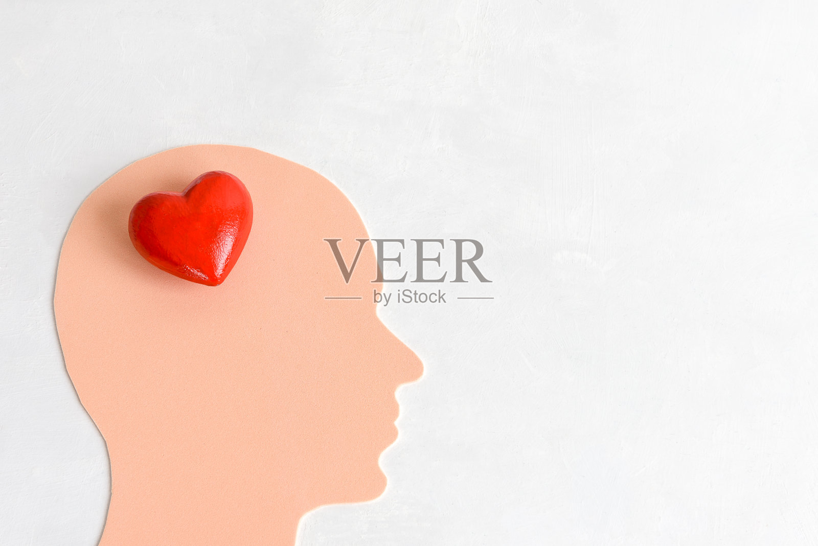 一个男人的头，里面有一颗心，在浅色的背景上。爱人或善良的人的概念。照片摄影图片