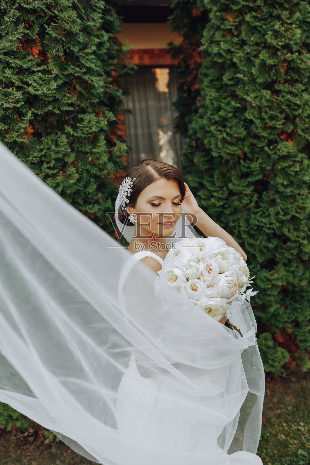 新娘手里捧着一束美丽的白色结婚花。公园里的户外照片。时尚的新娘。精致的妆照片摄影图片