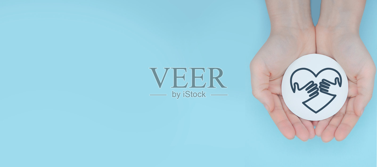 手持心形慈善标志，浅蓝色背景照片摄影图片