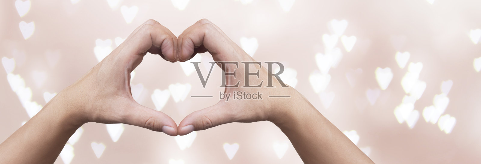 手在散焦的心形背景上形成心形照片摄影图片