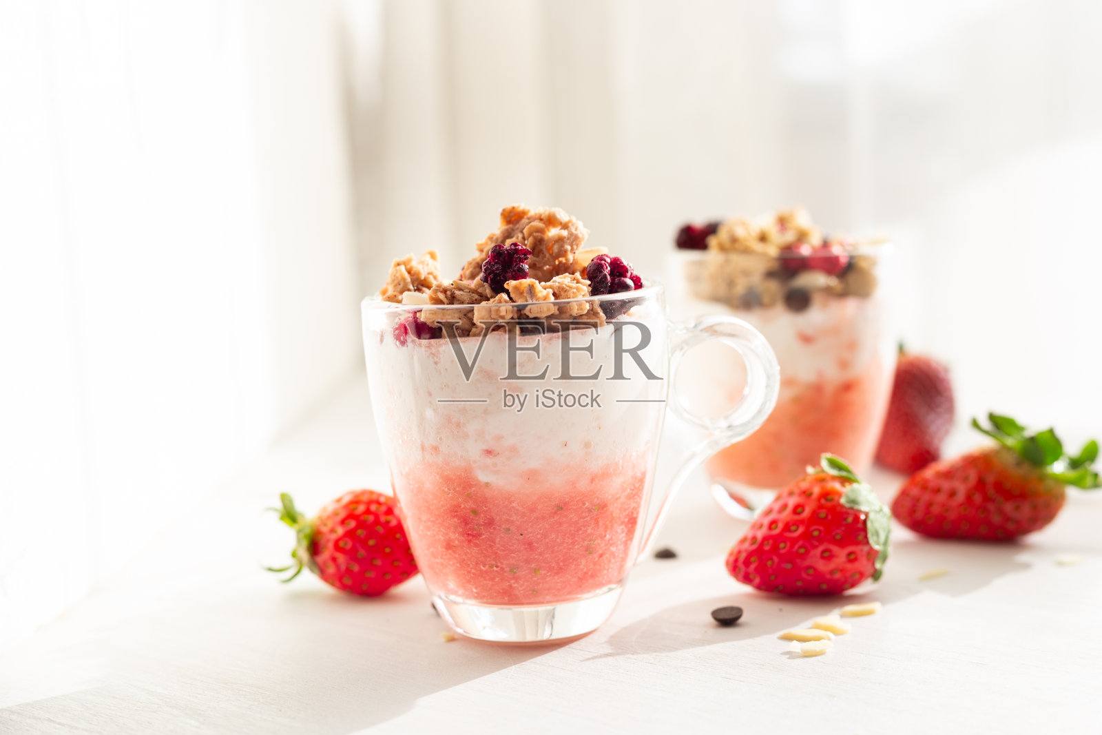 酸奶配红水果格兰诺拉麦片配草莓奶油、杏仁和巧克力片。给孩子们的健康零食。照片摄影图片