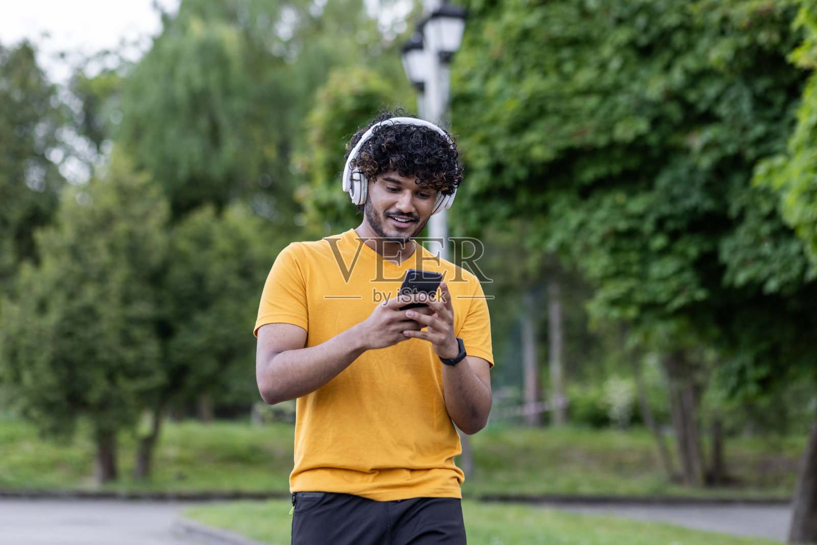 印度男子在公园健身时戴着耳机使用智能手机照片摄影图片