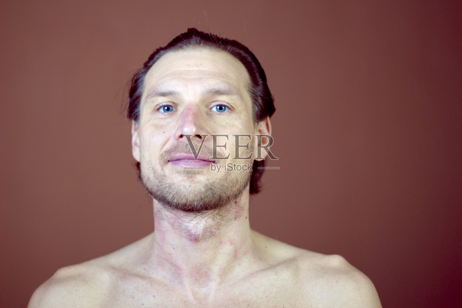 橙色背景上微笑的大胡子男人。蓝色的眼睛和光滑的头发。脸部特写。照片摄影图片