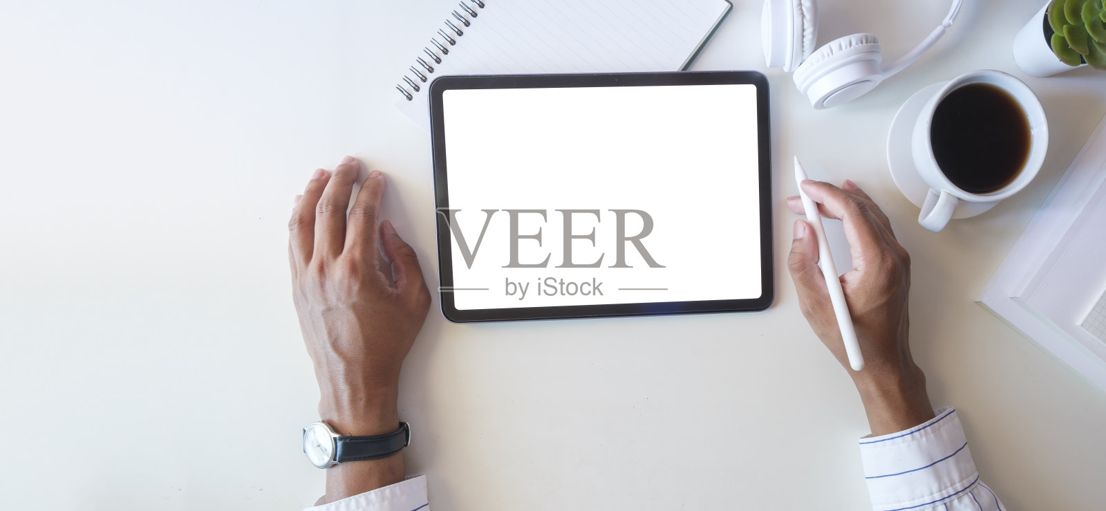 上图是创意人在办公桌上手持触控笔和使用数字平板电脑。照片摄影图片