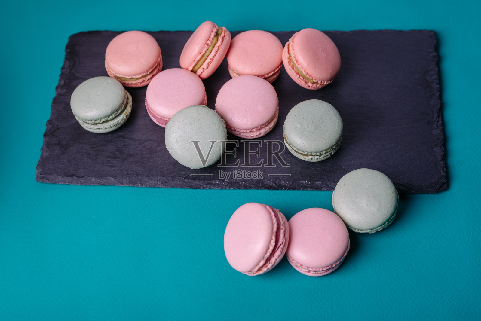 近彩色马卡龙甜点与复古柔和的色调在黑色石板。照片摄影图片