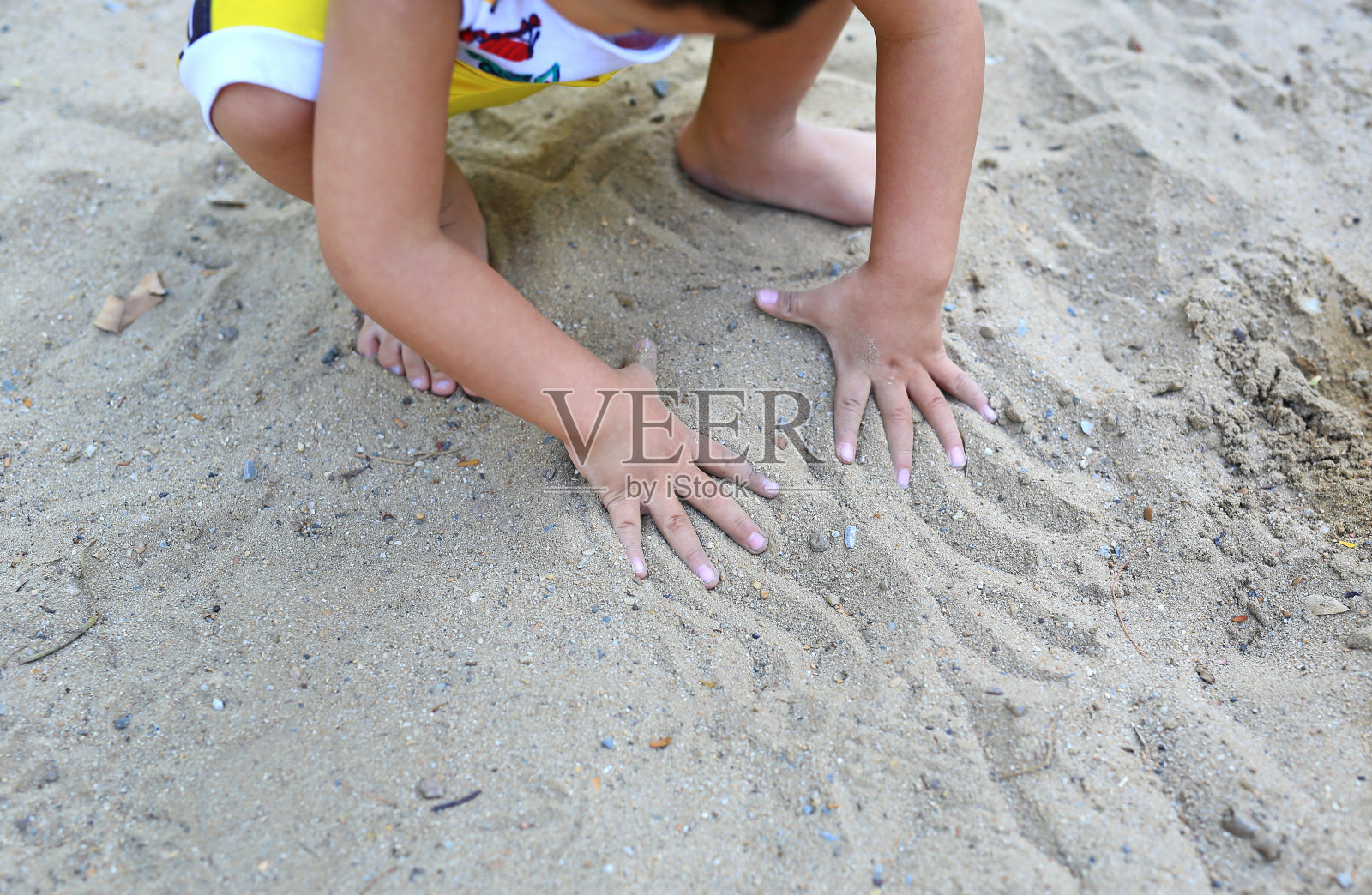 近距离拍摄婴儿在花园里玩土的手。照片摄影图片