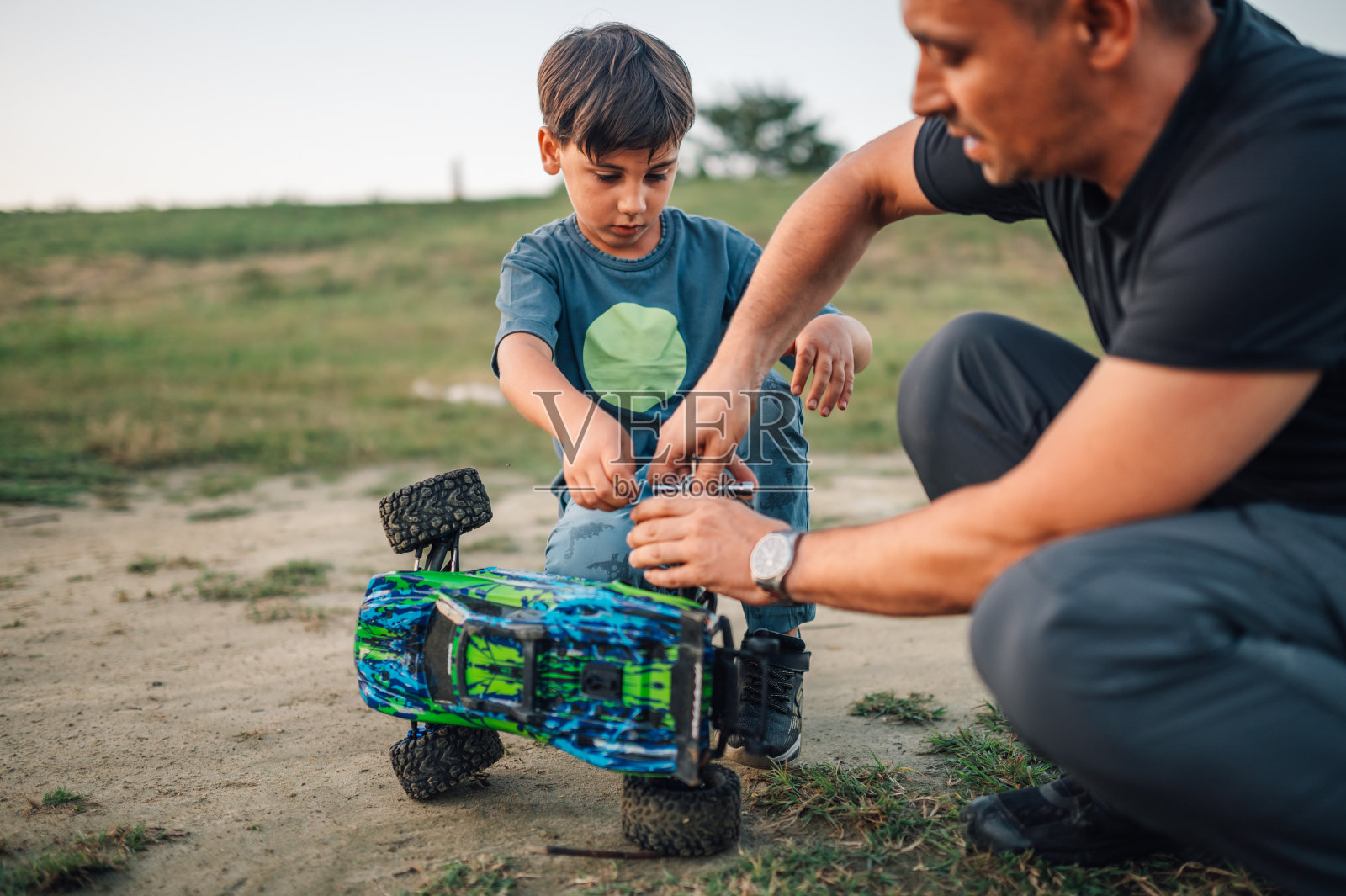 爸爸和儿子在户外玩耍时修理玩具卡车。照片摄影图片
