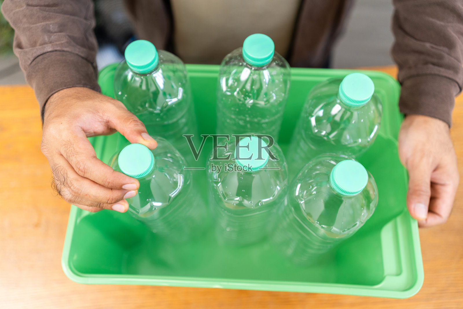 一个年轻人把塑料瓶放在一个盒子里。他认为塑料瓶在扔进垃圾箱之前会成为垃圾。世界环境日。回收废物，减少环境污染照片摄影图片