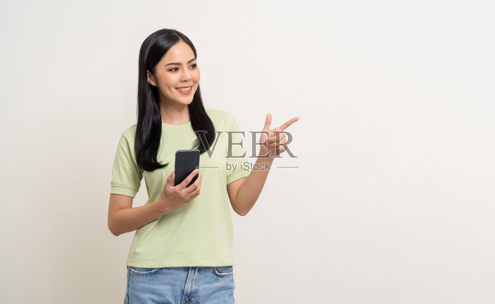 漂亮的年轻亚洲女人站在孤立的白色背景上使用手机。快乐兴奋美丽年轻的亚洲购物网上支付与手机。用智能手机玩游戏照片摄影图片