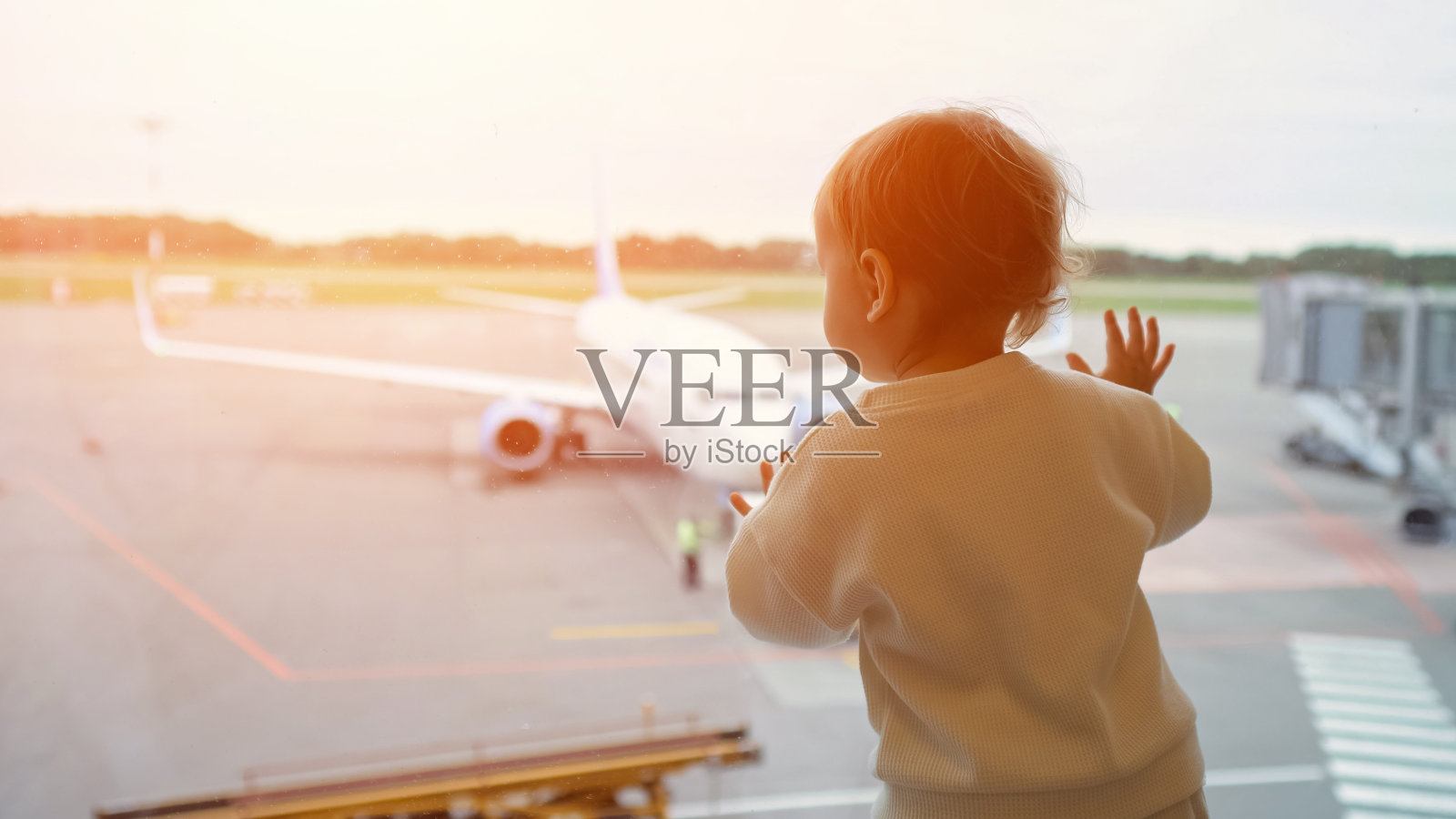 小孩透过大窗户看着飞机上的人照片摄影图片