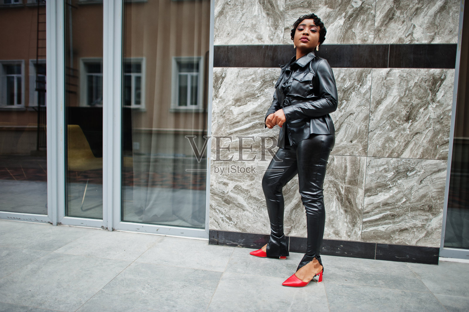 时尚美丽的非洲裔美国妇女在街头摆姿势黑色皮夹克和裤子。照片摄影图片