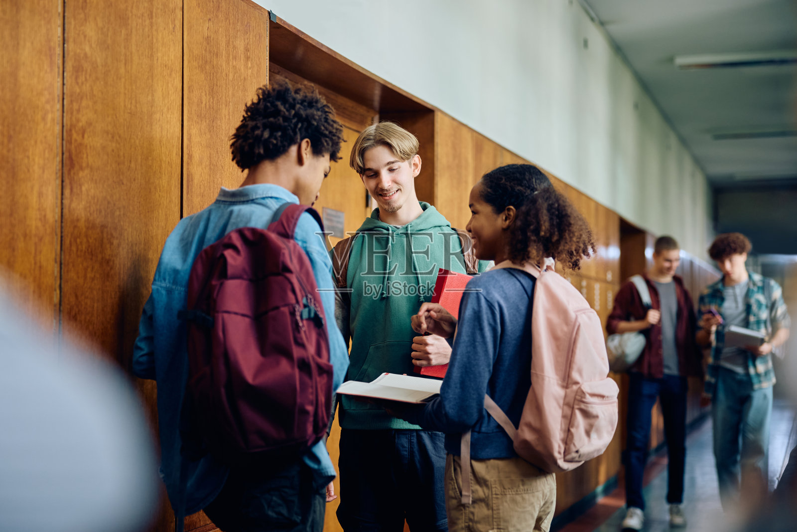快乐的学生和高中同学在学校走廊上聊天。照片摄影图片