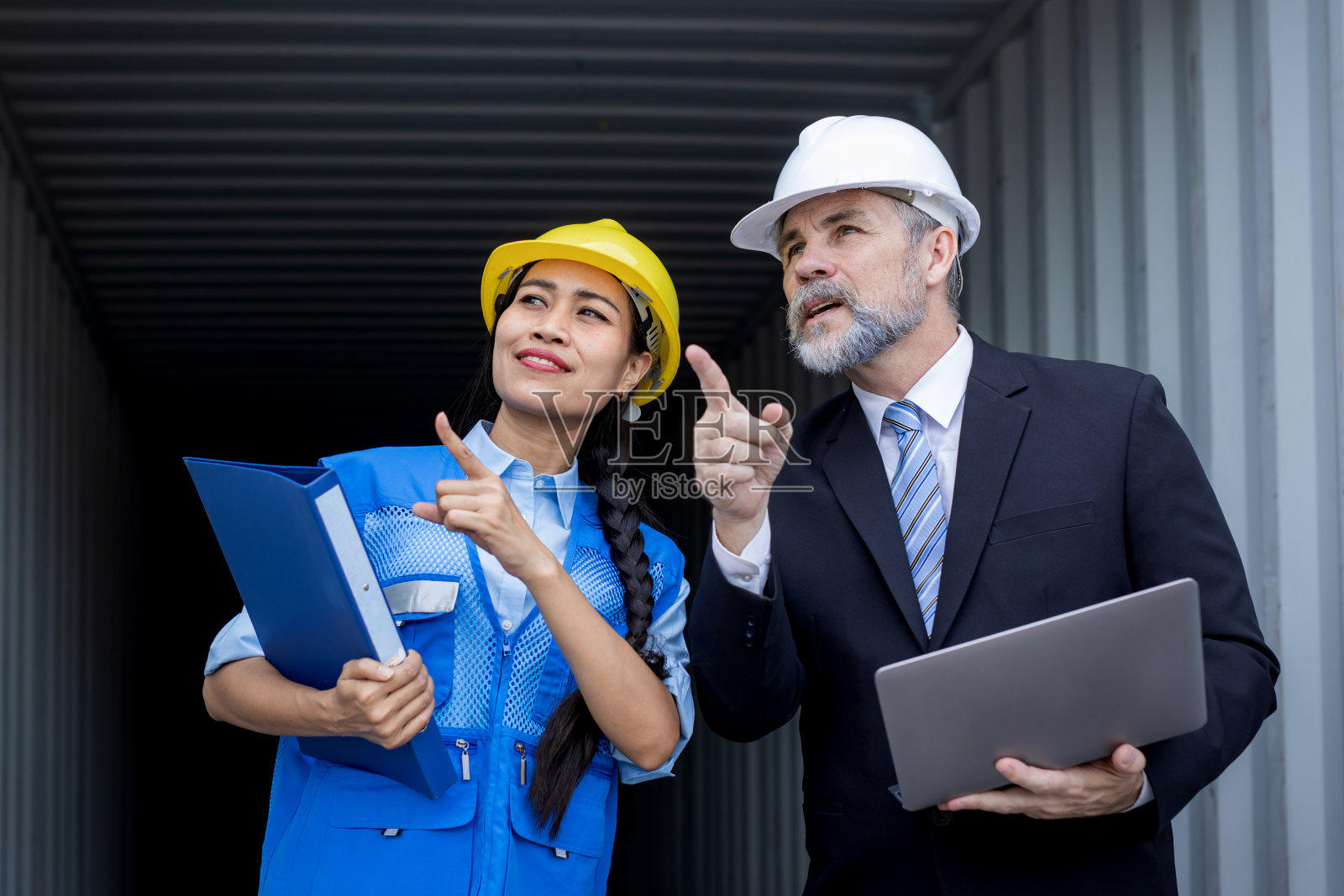 一名商人站在集装箱堆场前，手里拿着平板电脑，检查着通过港口的进出口订单清单。认真对待老板的工作，面对和解决物流货物中的问题照片摄影图片