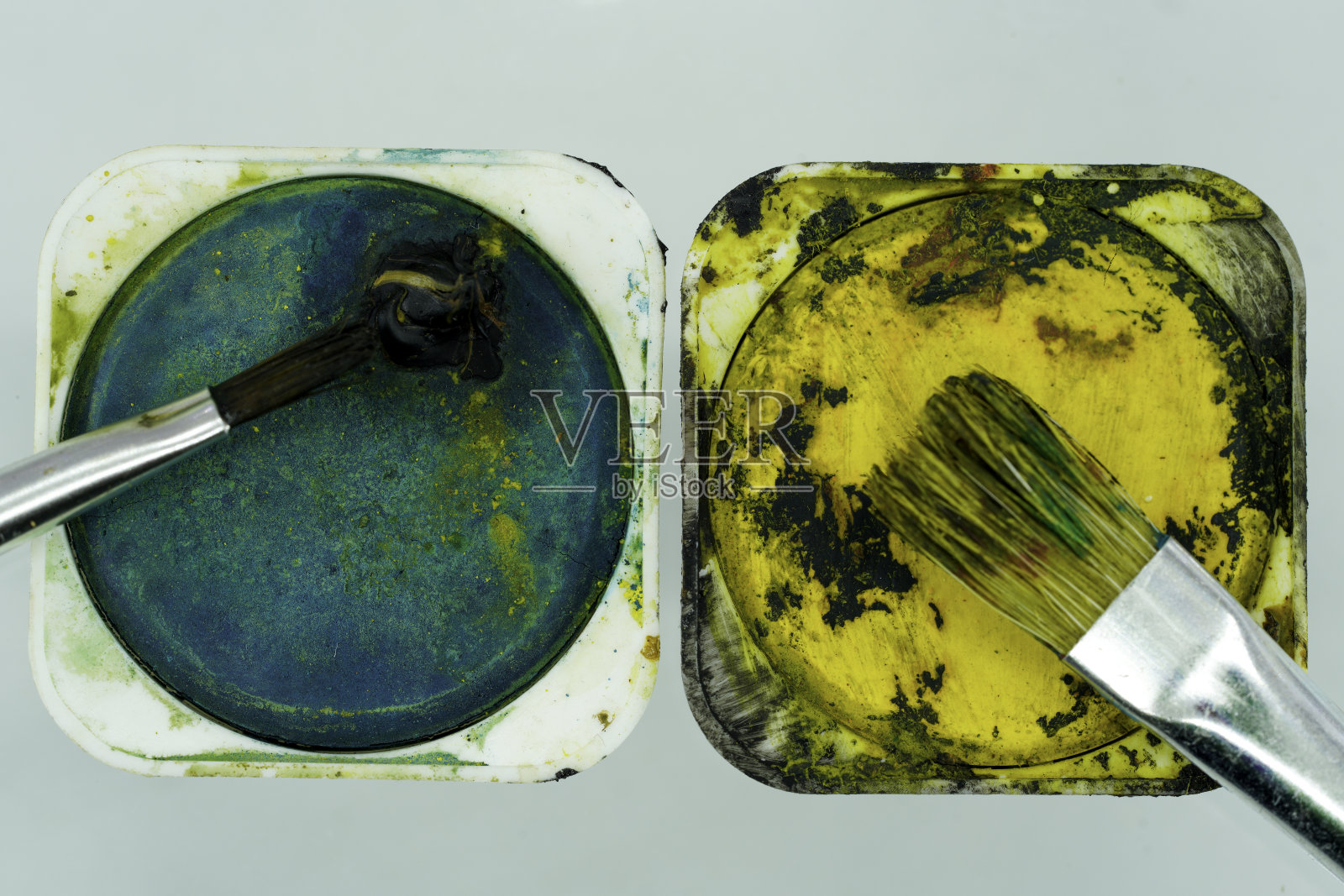 油漆刷和调色板用绿色和黄色的油漆在白色照片摄影图片