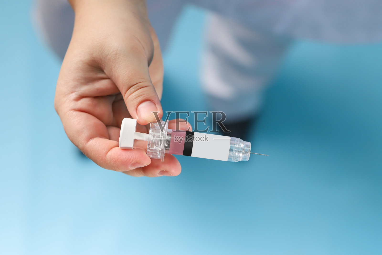 医生手中的注射器，蓝色背景的真实背景照片摄影图片