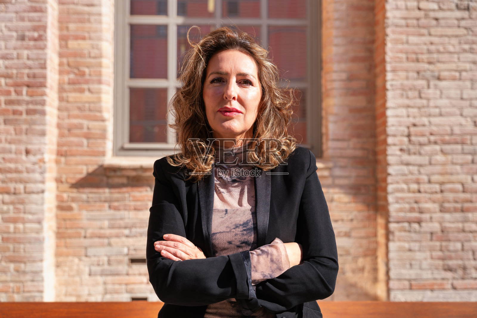 一位中年女商人双臂交叉站在户外。照片摄影图片