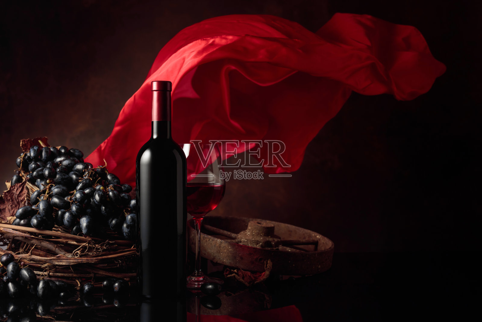 红酒配葡萄，以红色飘动的幕布为背景。照片摄影图片